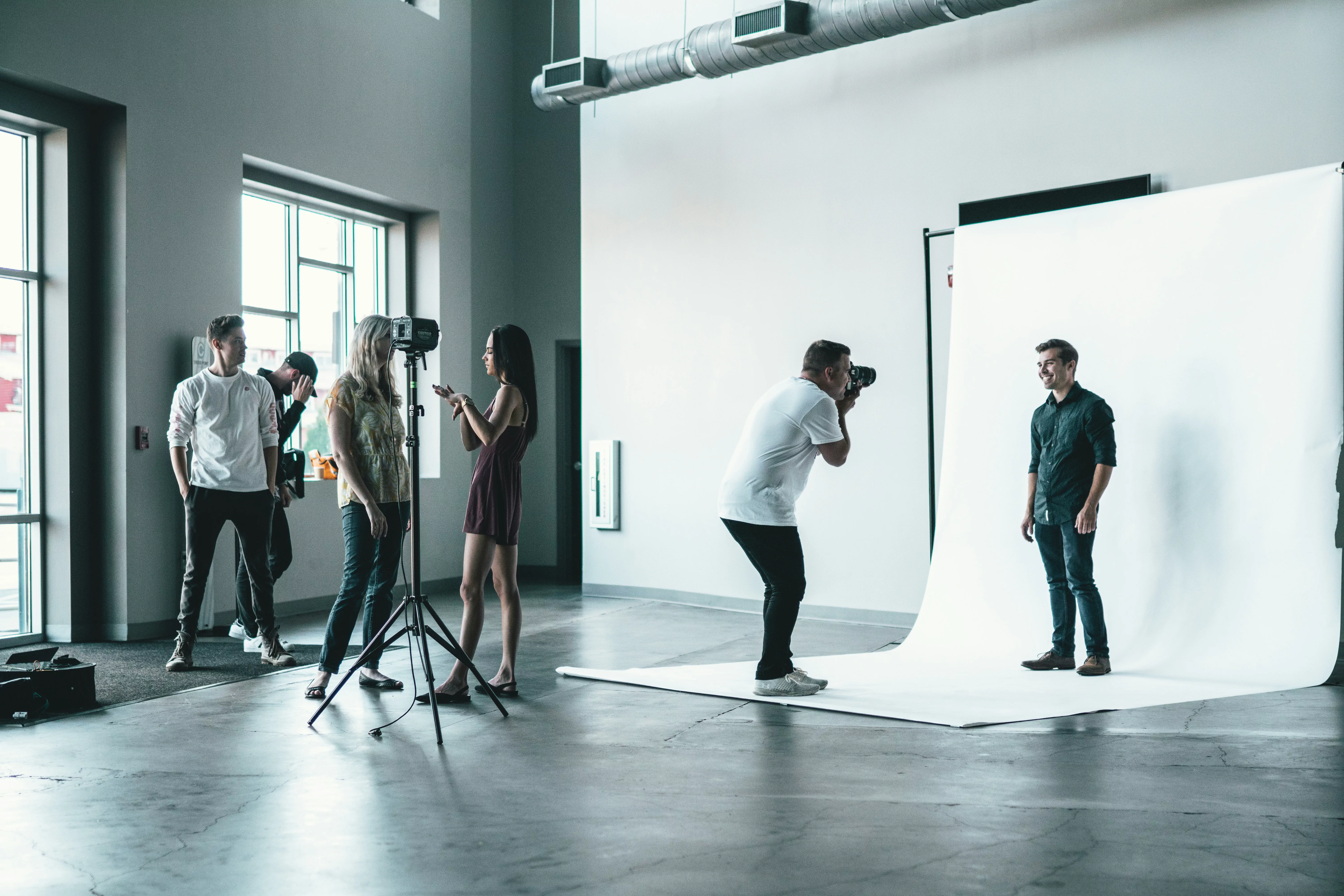 Expensive traditional photography studio session with professional photographer, lighting equipment, and high costs compared to AI headshot generator